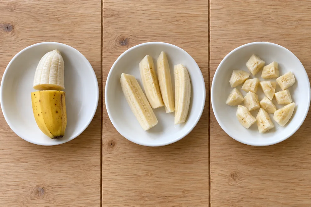 Banaan voor 6, 8 en 10 maanden: een halve banaan met schil als handvat, zachte partjes en kleine stukjes